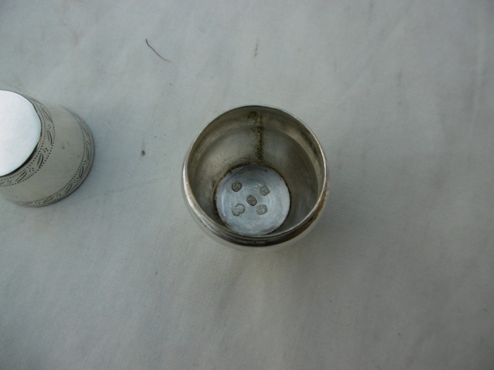 An antique Georgian sterling silver barrel-shaped nutmeg grater shown unscrewed into three component parts including cap, grater plate, and main body. View IV