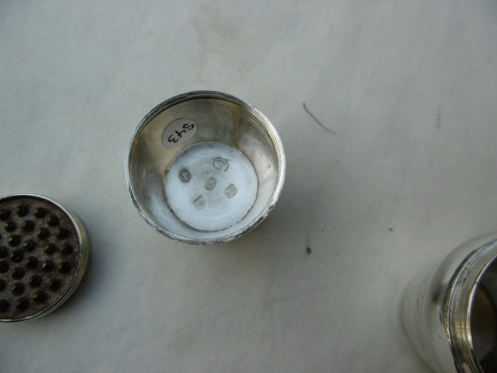 An antique Georgian sterling silver barrel-shaped nutmeg grater shown unscrewed into three component parts including cap, grater plate, and main body. View V