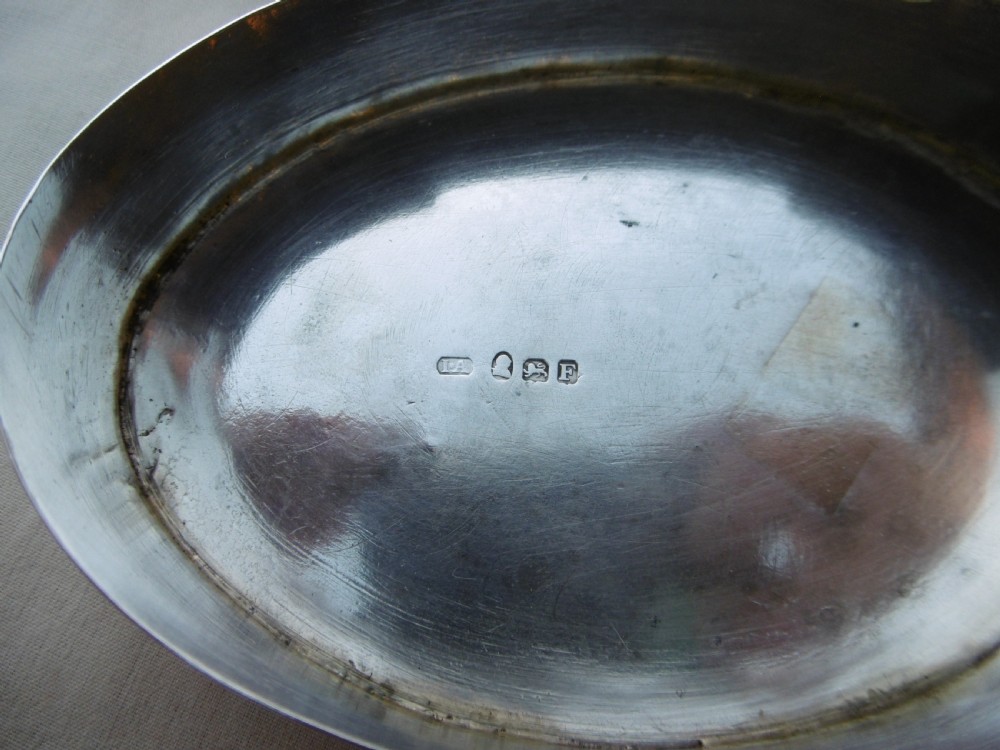An open oval Georgian sterling silver tobacco box displaying stamped British hallmarks inside the lid and base. View II