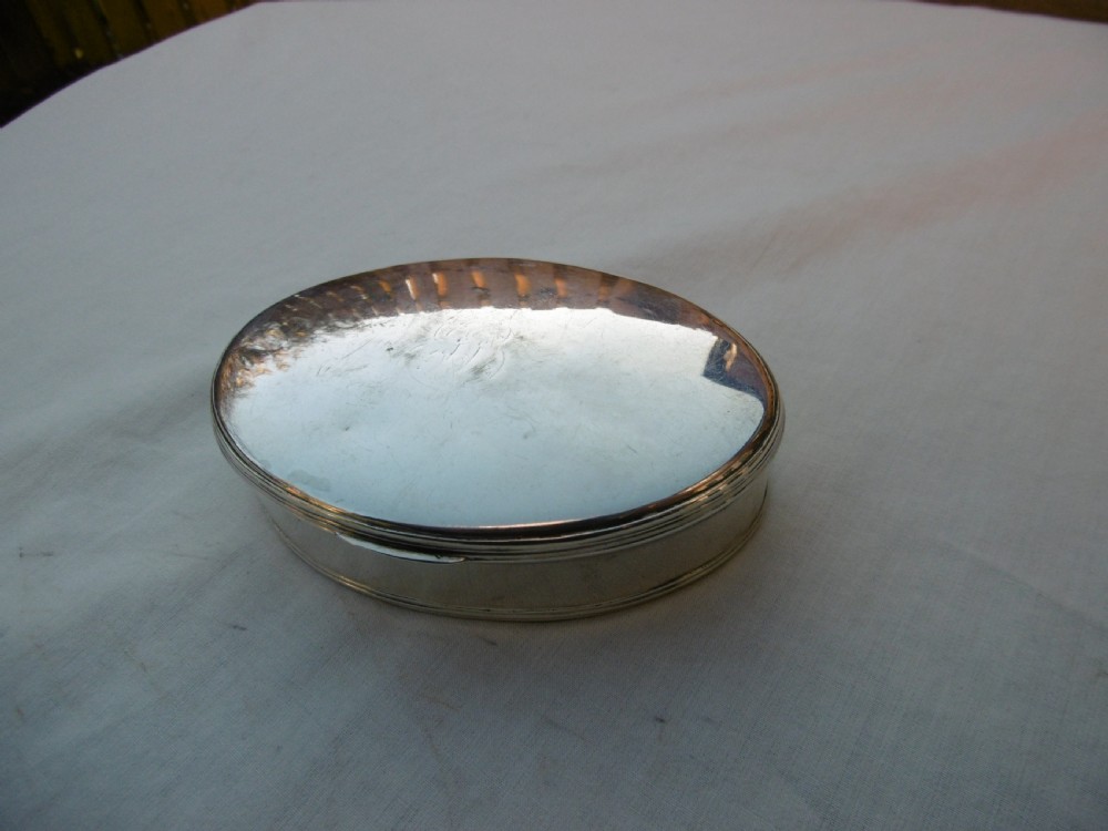 An open oval Georgian sterling silver tobacco box displaying stamped British hallmarks inside the lid and base. View IV