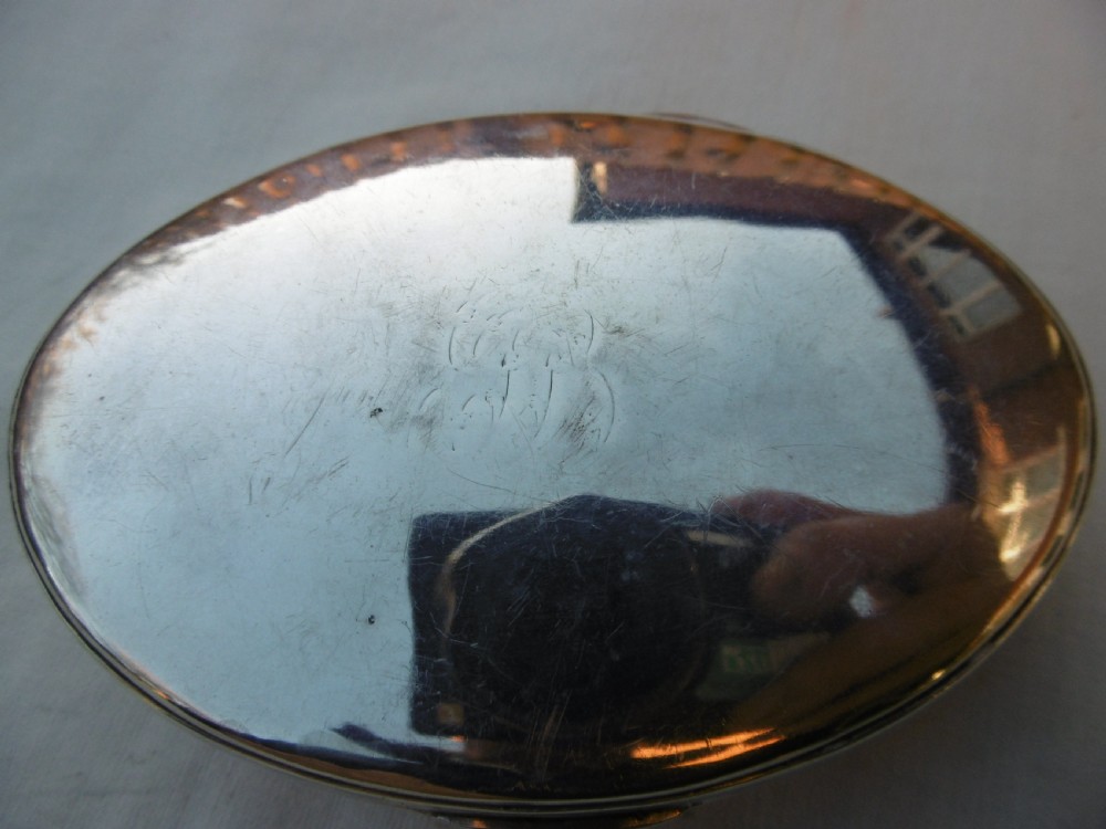 An open oval Georgian sterling silver tobacco box displaying stamped British hallmarks inside the lid and base. View V
