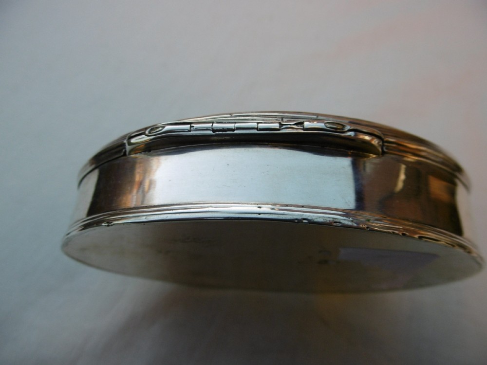 An open oval Georgian sterling silver tobacco box displaying stamped British hallmarks inside the lid and base. View VI