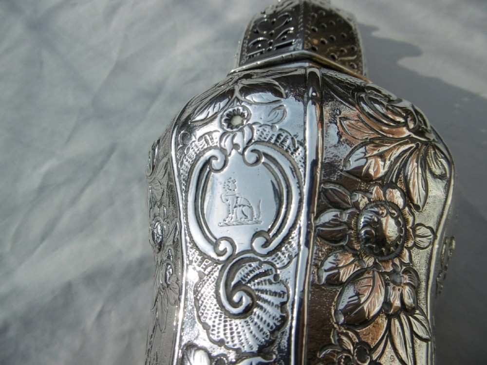 A Georgian sterling silver sugar castor featuring detailed floral chasing, a pierced dome lid, and a turned finial. View III