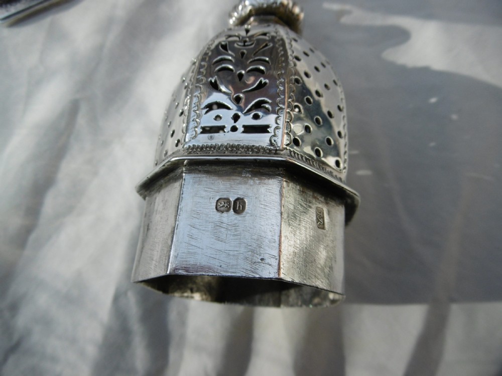 A Georgian sterling silver sugar castor featuring detailed floral chasing, a pierced dome lid, and a turned finial. View V