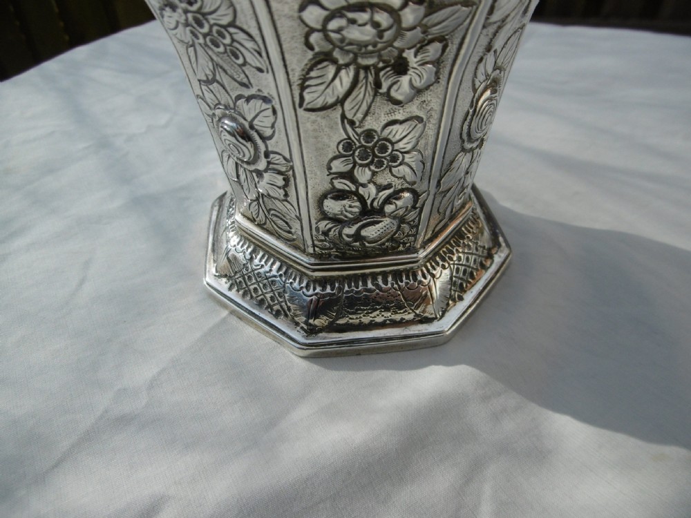 A Georgian sterling silver sugar castor featuring detailed floral chasing, a pierced dome lid, and a turned finial. View VI
