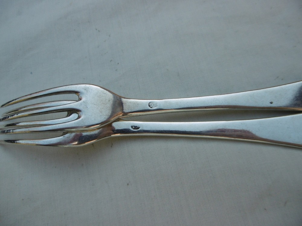 A pair of antique silver table forks featuring three tines and dognose handles engraved with armorial crests. View II