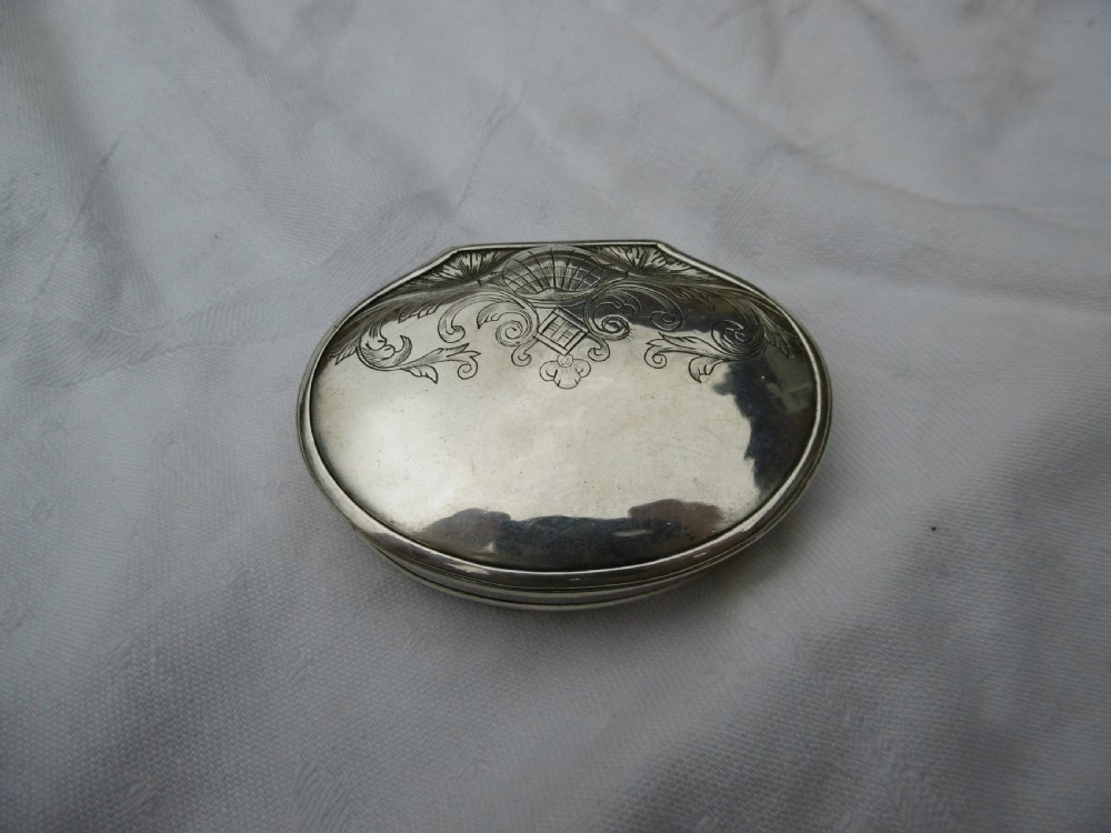 An eighteenth-century silver shell-shaped snuff box featuring hand-engraved scrollwork across the hinged lid.