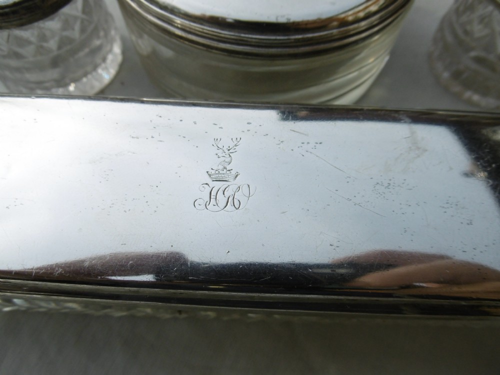 A five-piece Georgian sterling silver and cut glass dressing table set featuring engraved stag crests on silver lids. View IV
