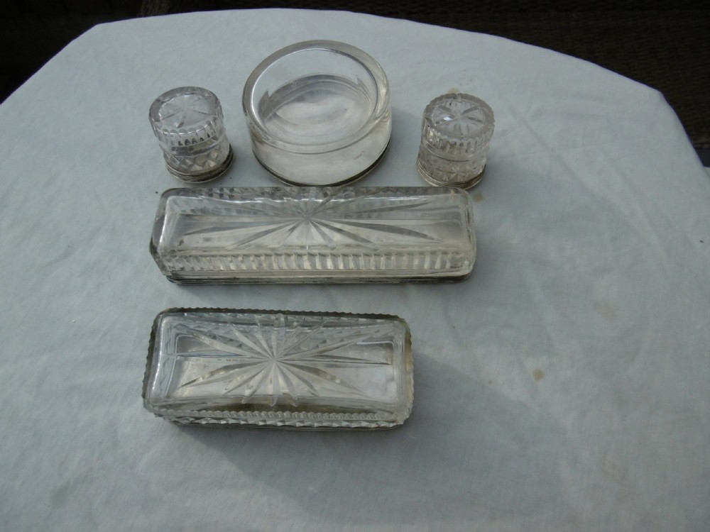 A five-piece Georgian sterling silver and cut glass dressing table set featuring engraved stag crests on silver lids. View V