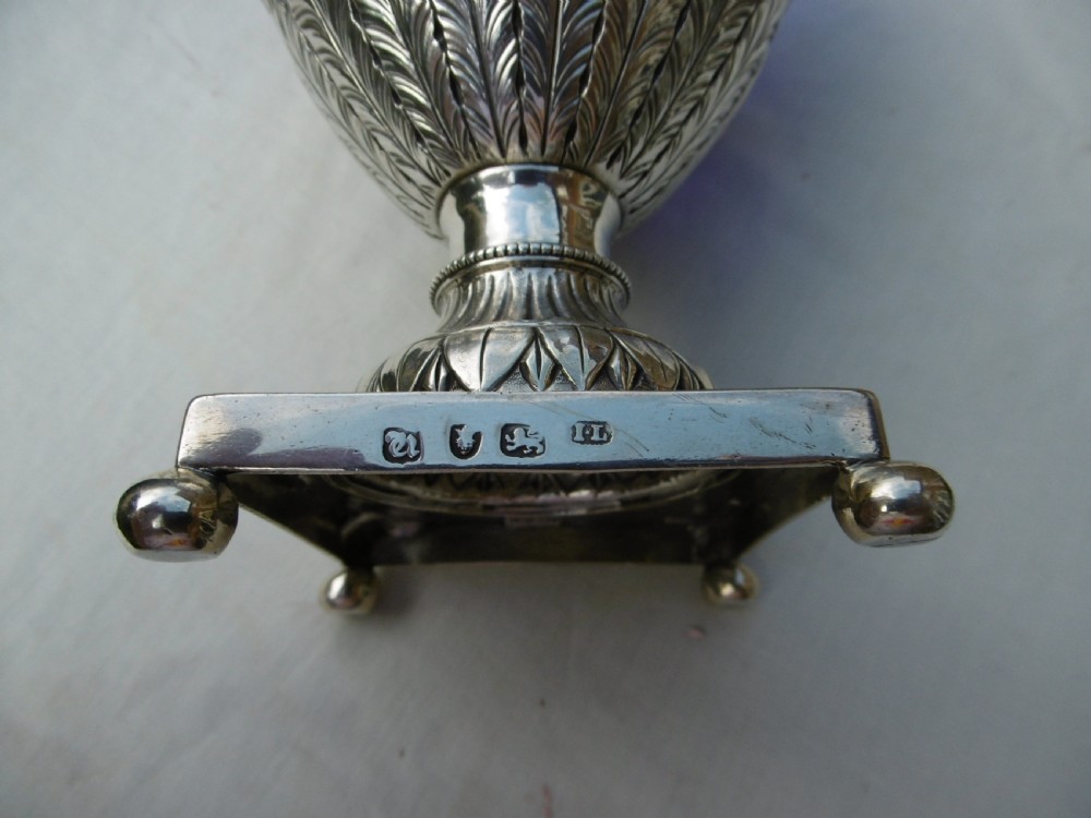 An 18th-century Adam style silver swing-handled basket with a cobalt blue glass liner, resting on a pedestal and square base with ball feet. View VI
