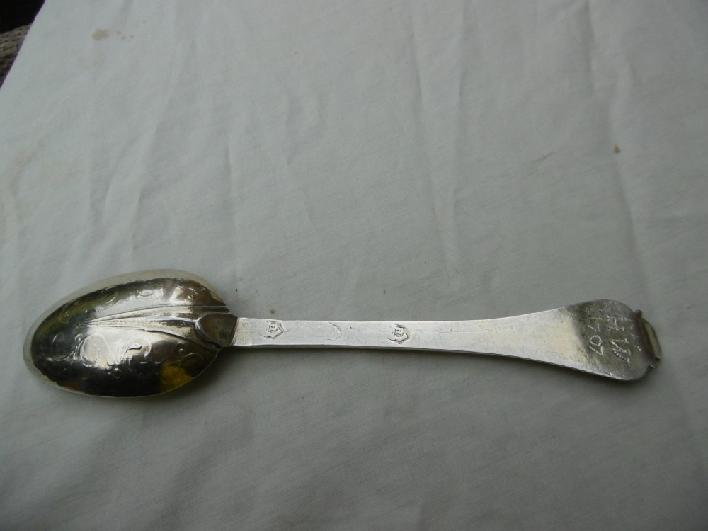 Reverse view of a silver tablespoon dated 1707 with a lace-back pattern and hallmarks along the handle. View II