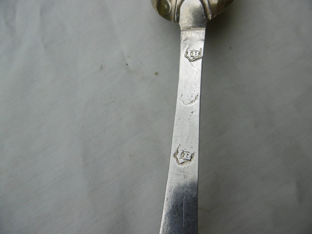 Reverse view of a silver tablespoon dated 1707 with a lace-back pattern and hallmarks along the handle. View III