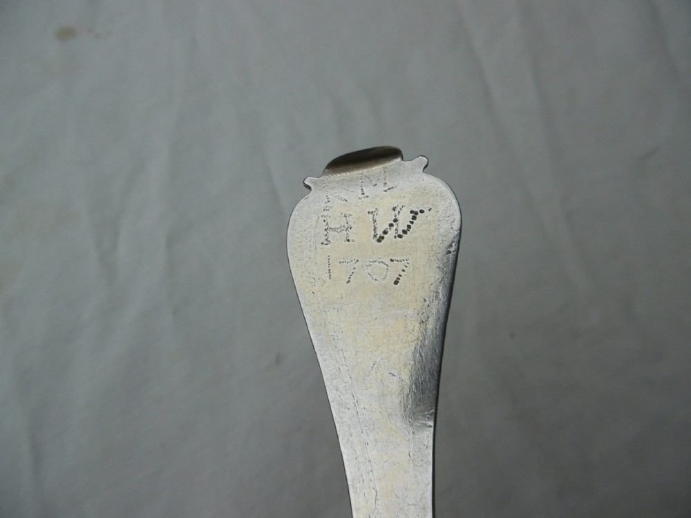 Reverse view of a silver tablespoon dated 1707 with a lace-back pattern and hallmarks along the handle. View V