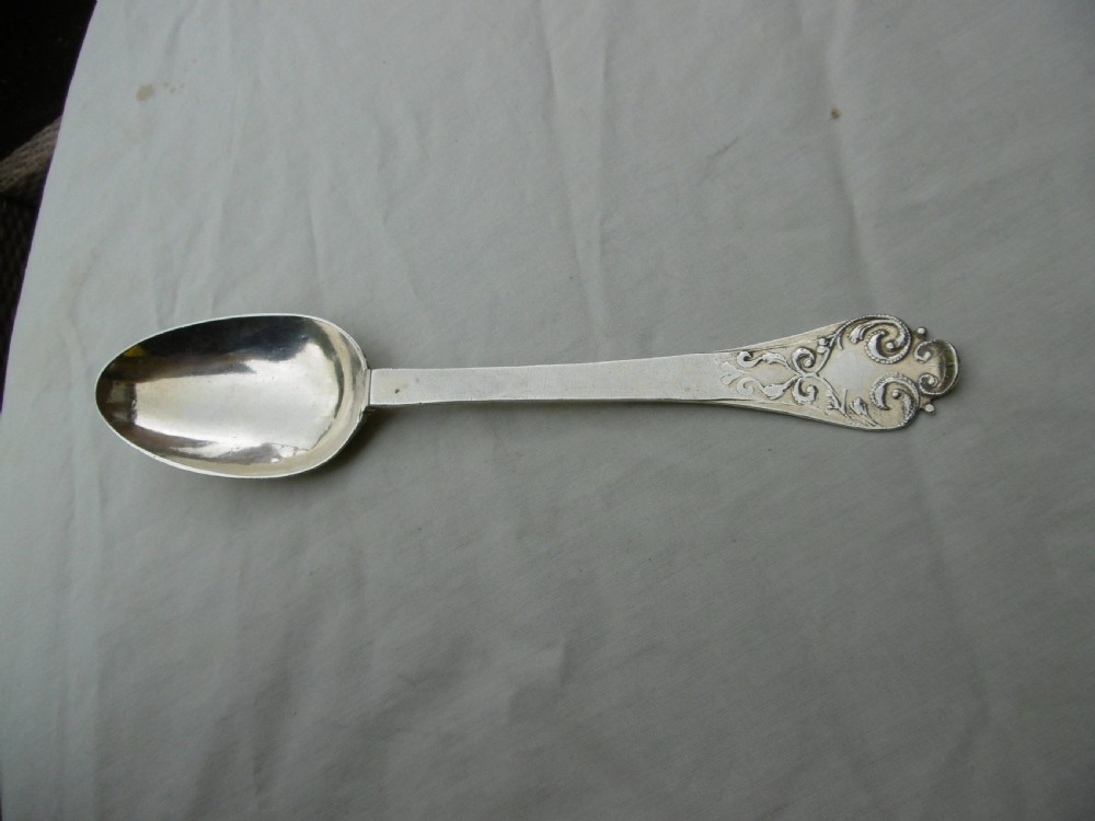 Reverse view of a silver tablespoon dated 1707 with a lace-back pattern and hallmarks along the handle. View VI