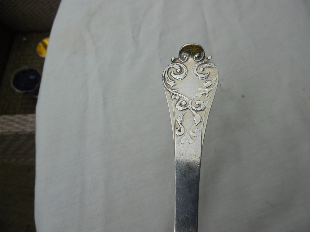 Reverse view of a silver tablespoon dated 1707 with a lace-back pattern and hallmarks along the handle. View VII