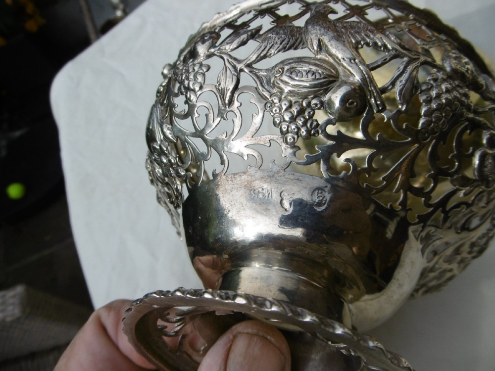 An 18th-century Irish Georgian sterling silver basket featuring pierced lattice work, floral motifs, a pedestal base, and an arched swing handle. View III