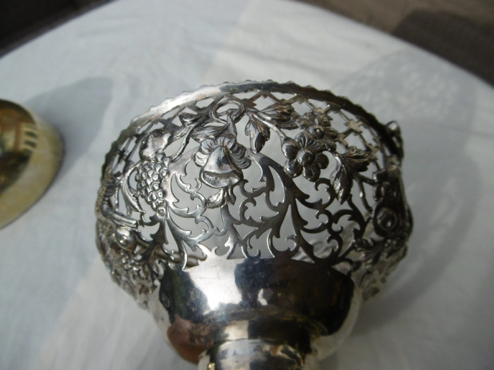 An 18th-century Irish Georgian sterling silver basket featuring pierced lattice work, floral motifs, a pedestal base, and an arched swing handle. View IV