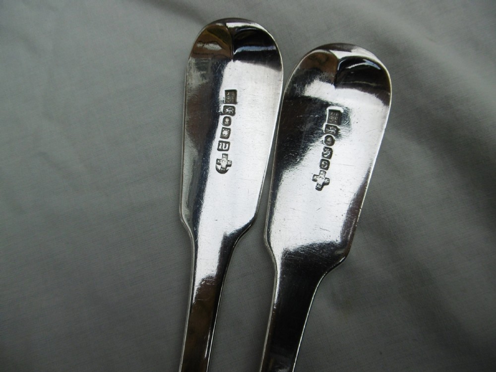 A pair of Georgian sterling silver soup ladles featuring Fiddle pattern handles engraved with crests and deep round silver bowls. View II