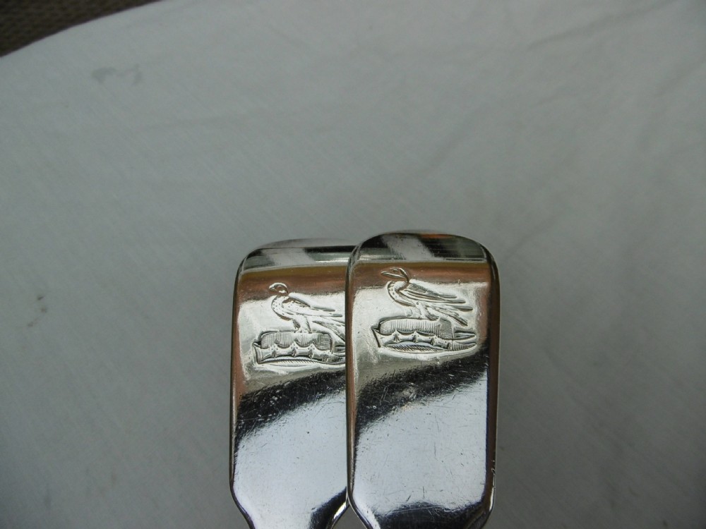 A pair of Georgian sterling silver soup ladles featuring Fiddle pattern handles engraved with crests and deep round silver bowls. View VII