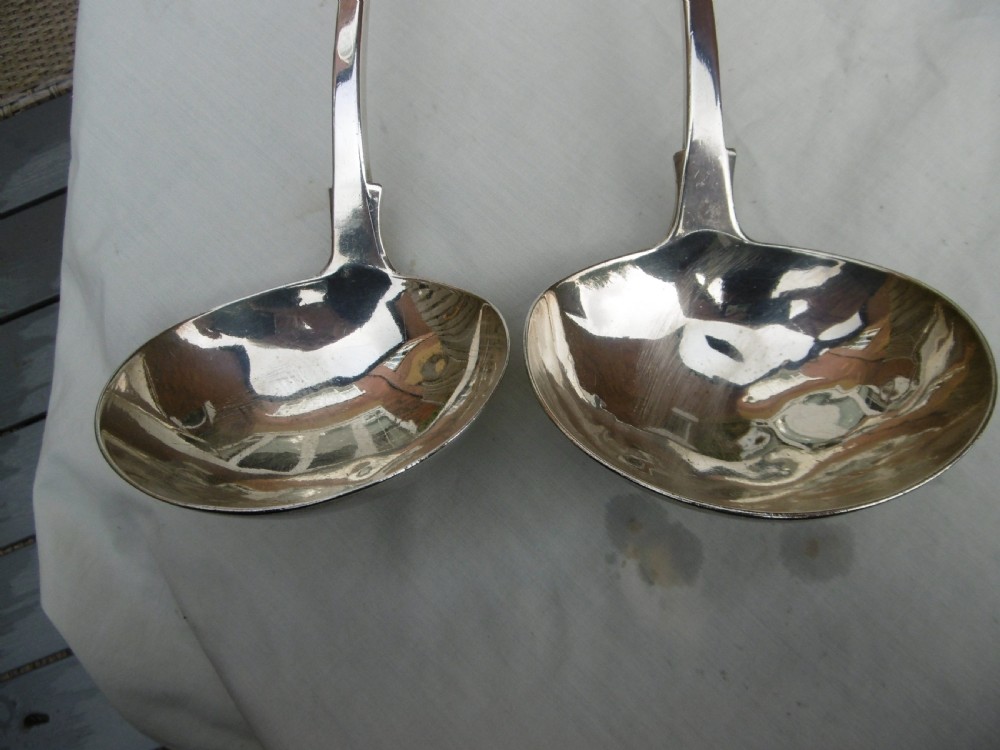 A pair of Georgian sterling silver soup ladles featuring Fiddle pattern handles engraved with crests and deep round silver bowls. View VIII