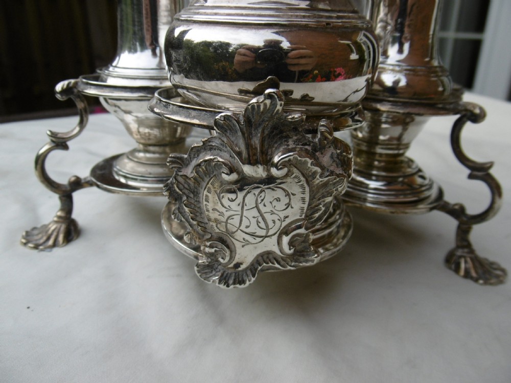 An 18th-century Georgian sterling silver Warwick cruet frame holding silver casters and cut glass bottles set upon shell-form feet. View II