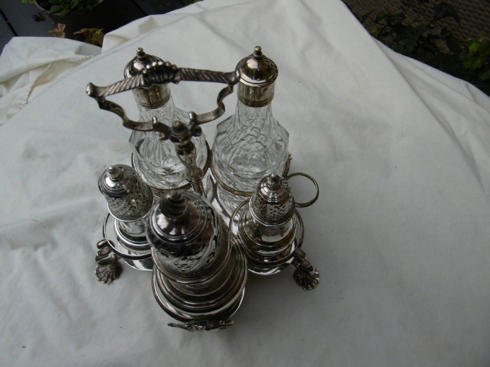 An 18th-century Georgian sterling silver Warwick cruet frame holding silver casters and cut glass bottles set upon shell-form feet. View III