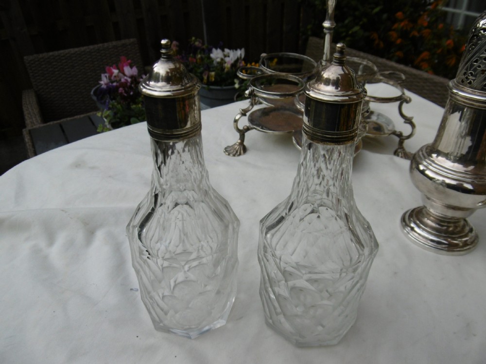 An 18th-century Georgian sterling silver Warwick cruet frame holding silver casters and cut glass bottles set upon shell-form feet. View V