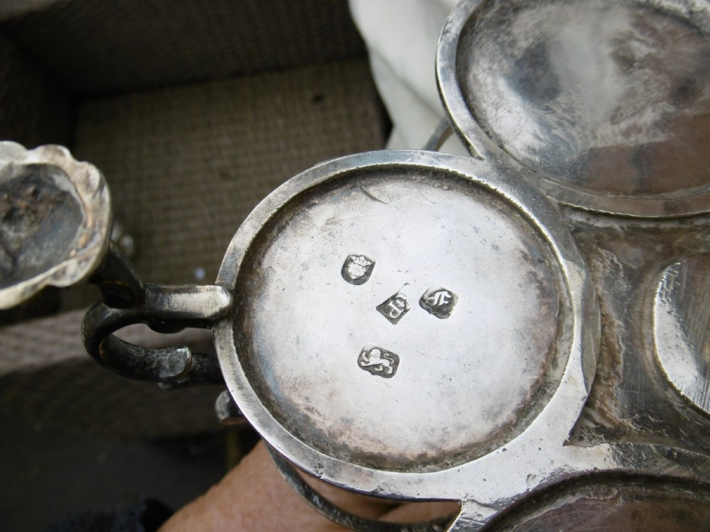 An 18th-century Georgian sterling silver Warwick cruet frame holding silver casters and cut glass bottles set upon shell-form feet. View XI