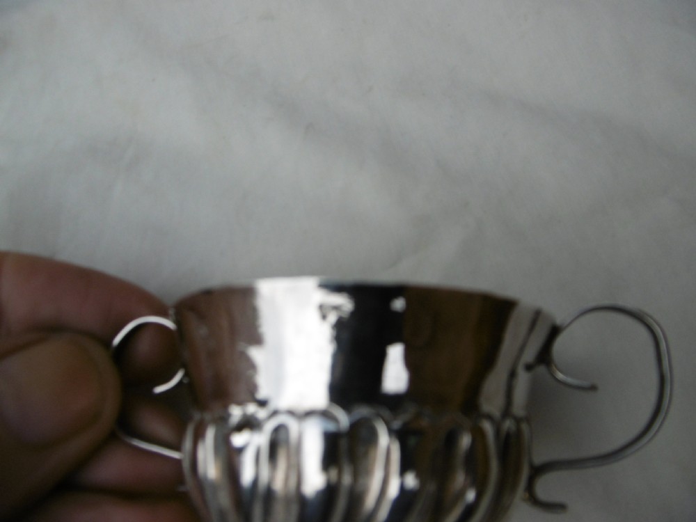 A small late 17th-century silver porringer featuring two wire handles and spiral fluted embossing around the lower half of the bowl. View III