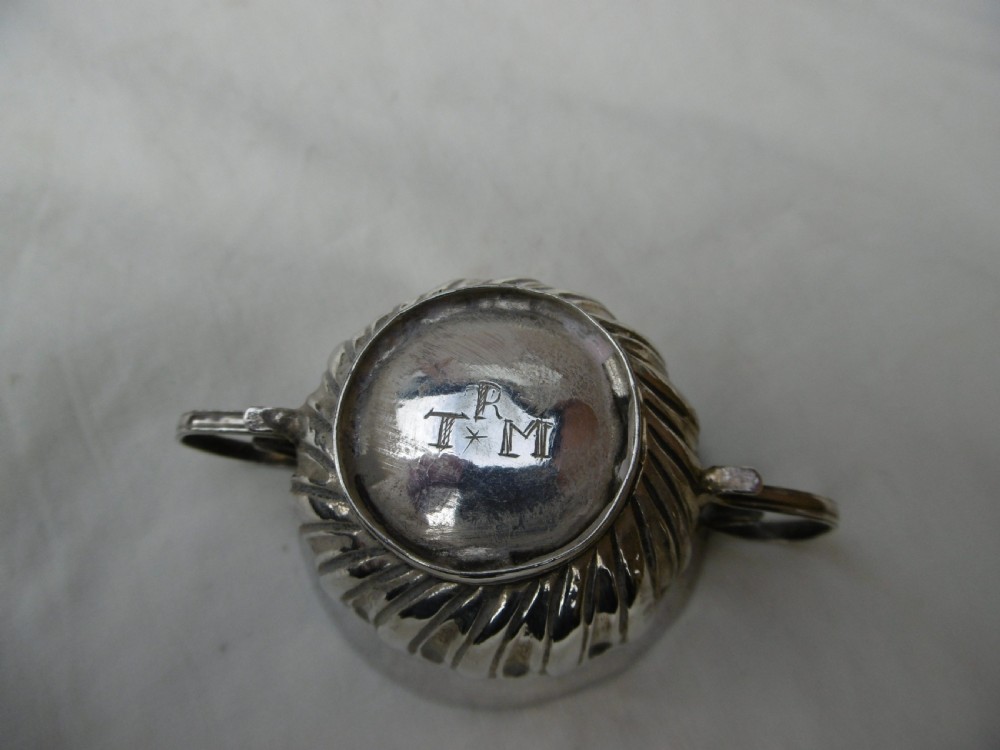 A small late 17th-century silver porringer featuring two wire handles and spiral fluted embossing around the lower half of the bowl. View VI