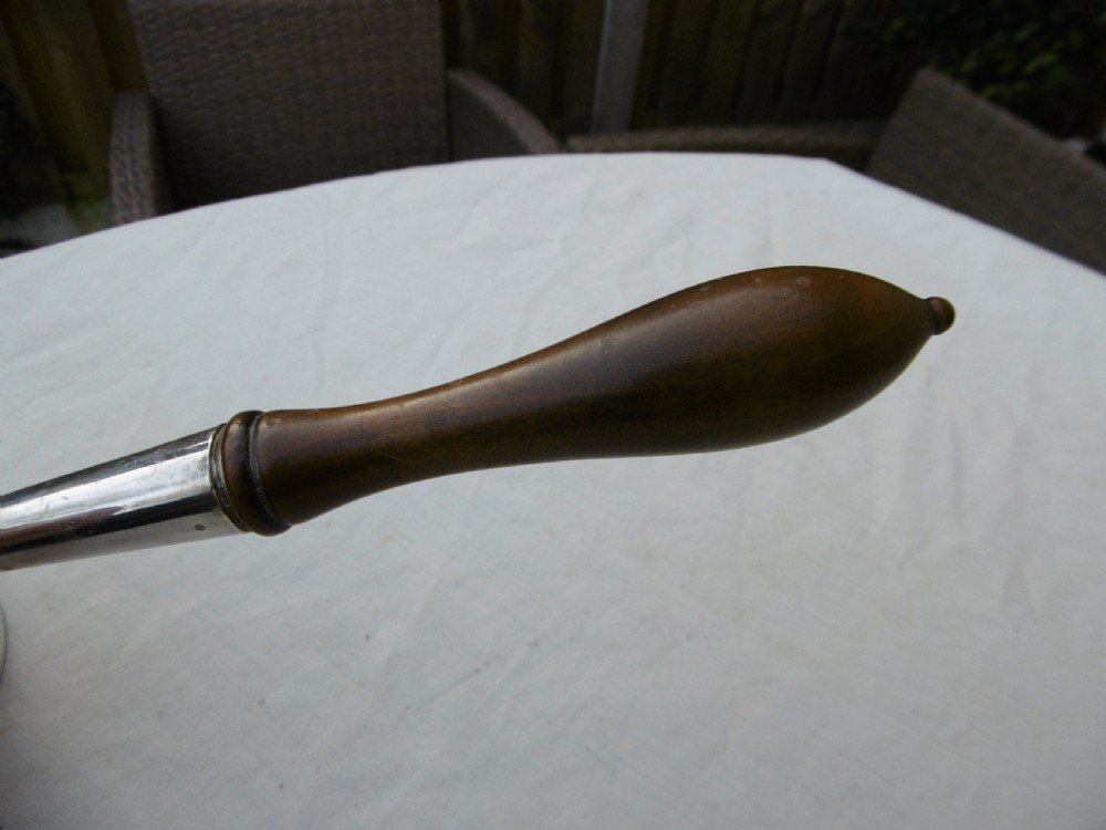 A George I silver brandy pan featuring a flared rim, plain cylindrical body, and a long turned dark wood handle. View V
