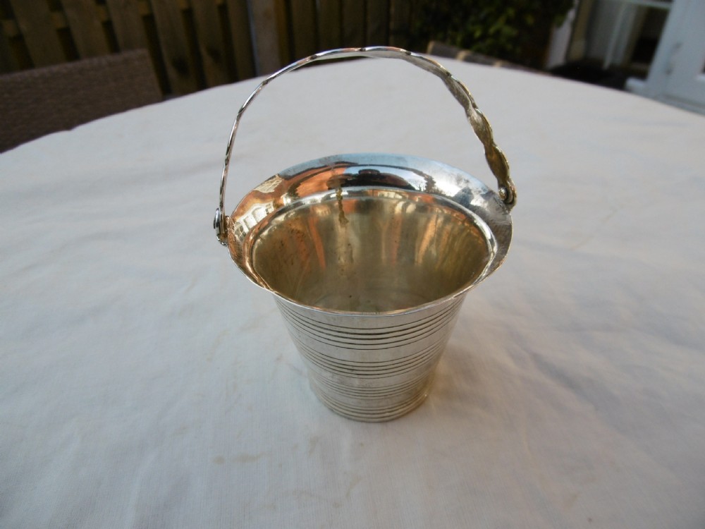 A George II sterling silver cream pail with a reeded bucket body and an overhead swing handle.