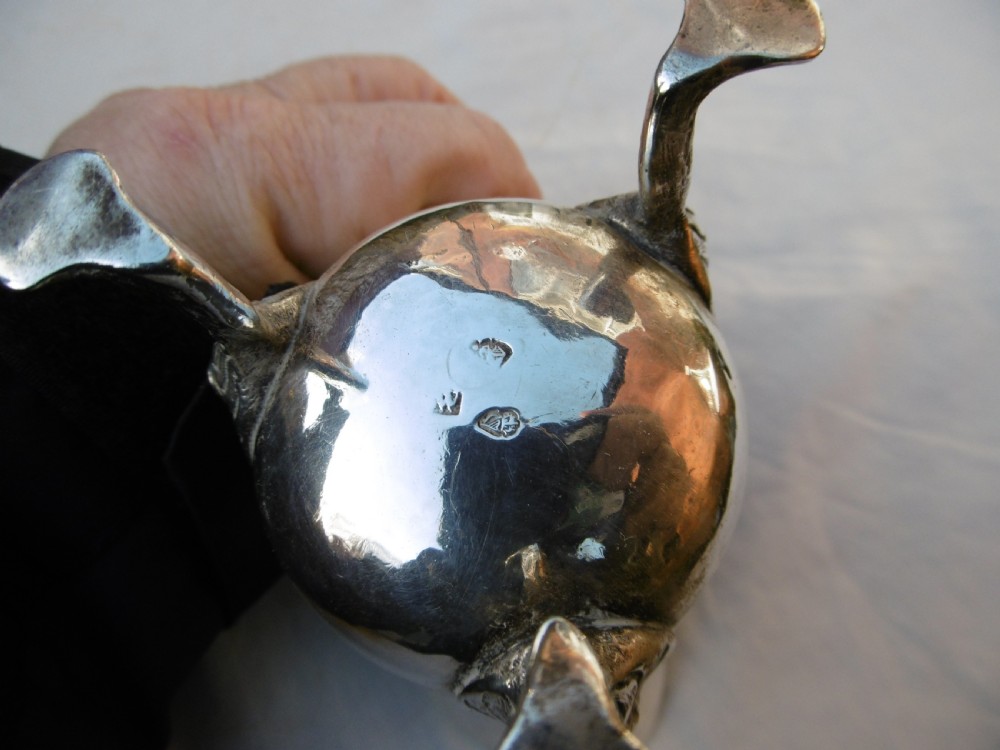An 18th-century Georgian Irish silver helmet-shaped cream jug with a scalloped rim, scroll handle, and three lion mask feet. View II