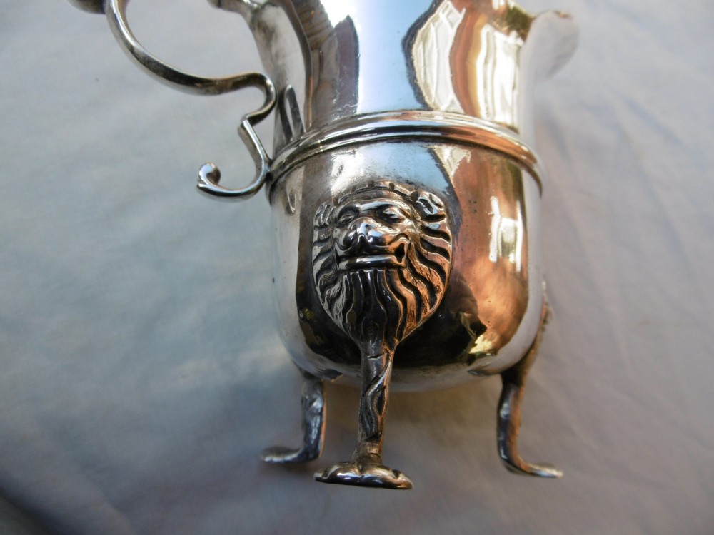 An 18th-century Georgian Irish silver helmet-shaped cream jug with a scalloped rim, scroll handle, and three lion mask feet. View III