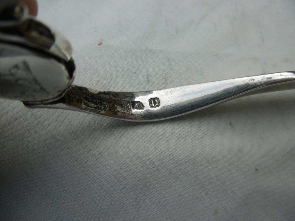 A pair of 1799 George III sterling silver serving tongs featuring a circular central boss with an engraved crest, curved arms, and a sliding restraint bar. View IV