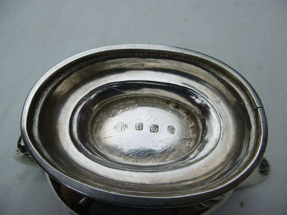 A 1778 Georgian sterling silver sauce boat featuring a beaded rim, a scroll handle, and a oval pedestal foot. View II