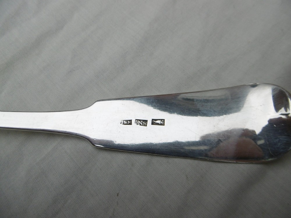 A Georgian Scottish provincial sterling silver soup ladle with a polished circular bowl and a long curved flat handle against a plain background. View II
