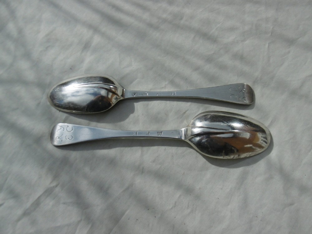 A pair of early eighteenth-century silver tablespoons displayed from the reverse, highlighting the rat-tail bowl joins, hallmarks, and initials.