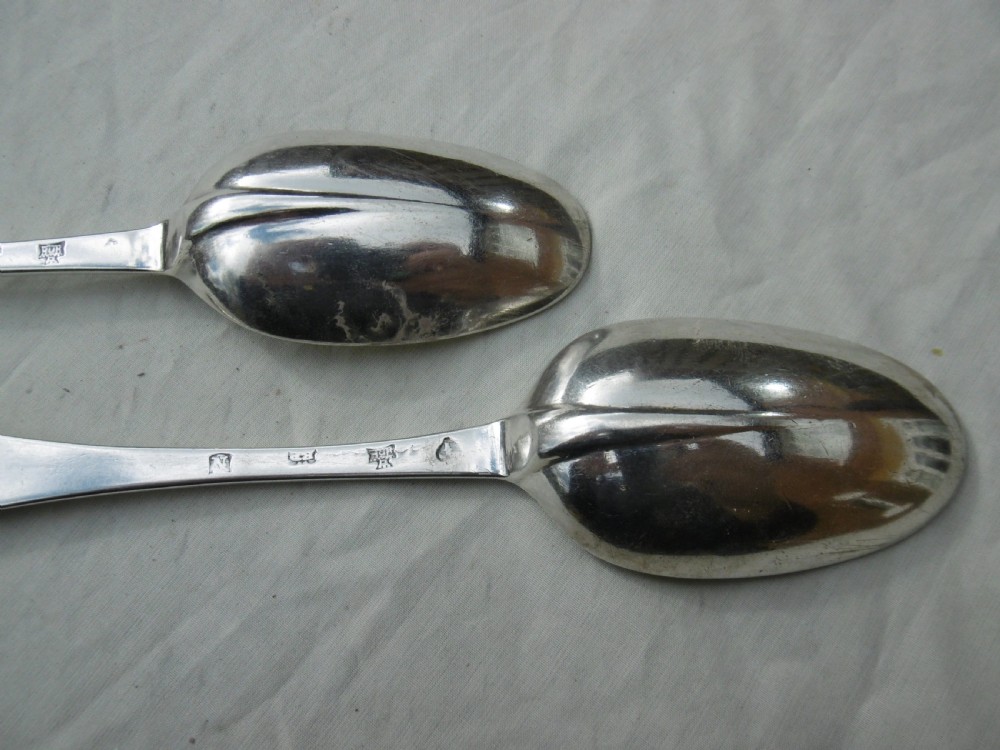 A pair of early eighteenth-century silver tablespoons displayed from the reverse, highlighting the rat-tail bowl joins, hallmarks, and initials. View V