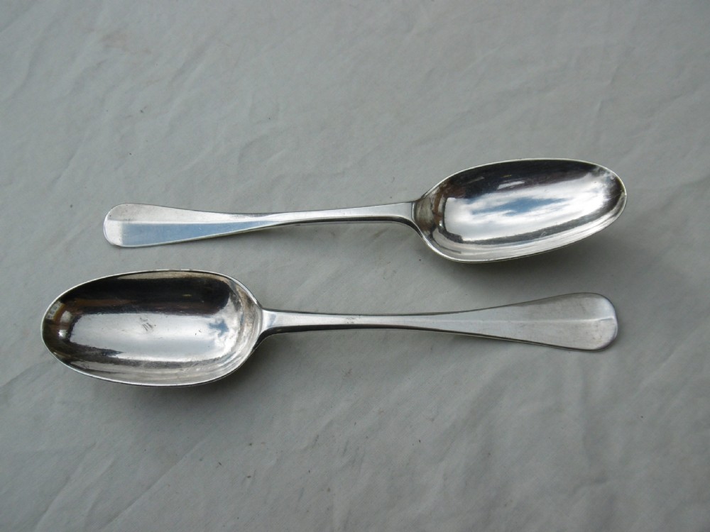 A pair of early eighteenth-century silver tablespoons displayed from the reverse, highlighting the rat-tail bowl joins, hallmarks, and initials. View VI