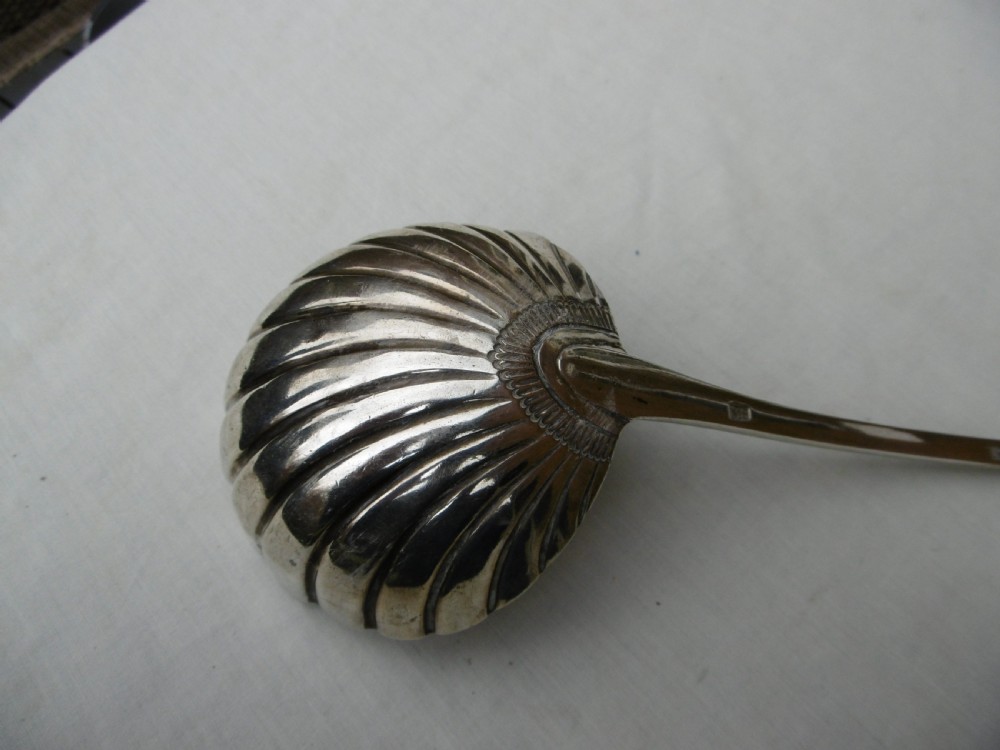 An 18th-century Georgian sterling silver soup ladle with an engraved crest on the handle and a fluted shell bowl. View II