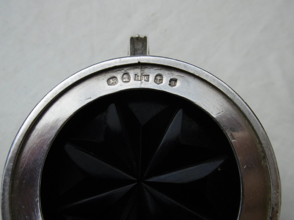 A circular Georgian sterling silver mustard pot featuring a hinged lid with a leaf motif finial and gadrooned border. View II