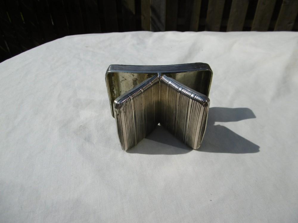 An antique sterling silver double-lidded snuff box featuring reeded linear engraving and interior silver hallmarks.