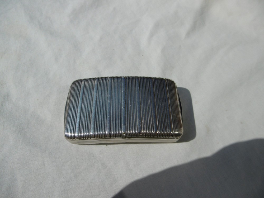 An antique sterling silver double-lidded snuff box featuring reeded linear engraving and interior silver hallmarks. View II