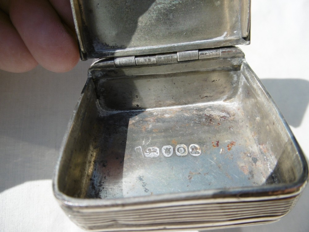 An antique sterling silver double-lidded snuff box featuring reeded linear engraving and interior silver hallmarks. View III