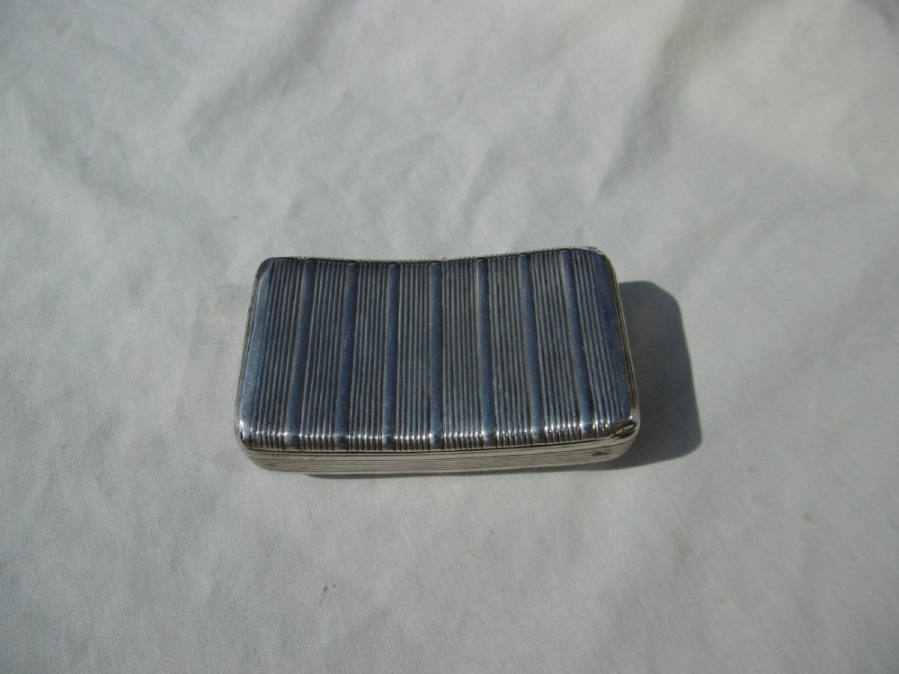 An antique sterling silver double-lidded snuff box featuring reeded linear engraving and interior silver hallmarks. View IV