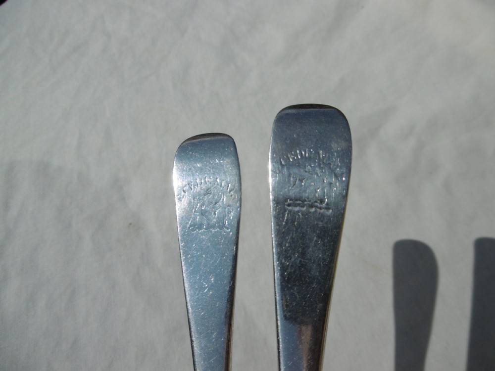 A pair of early 18th-century George I Britannia standard silver three-pronged forks displayed on a white fabric surface. View IV