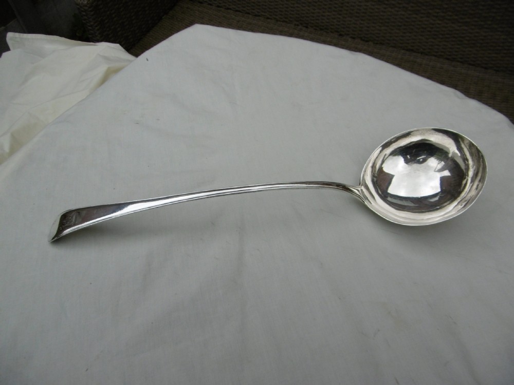 A Georgian sterling silver soup ladle featuring a long curved stem, a circular bowl, and official assay hallmarks near the terminal.