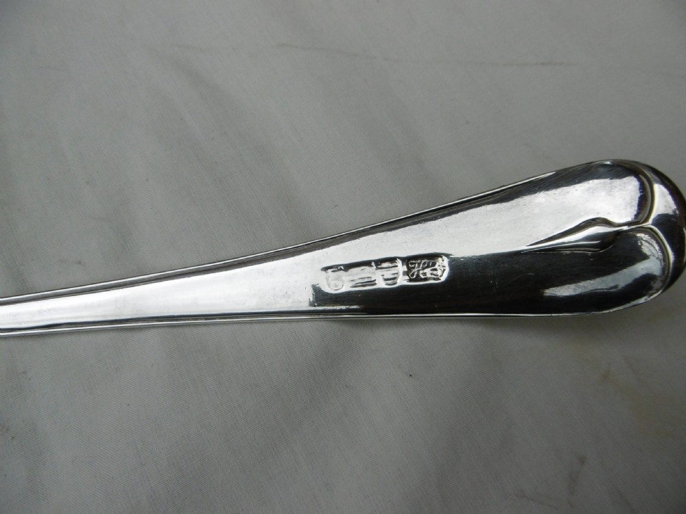 A Georgian sterling silver soup ladle featuring a long curved stem, a circular bowl, and official assay hallmarks near the terminal. View II