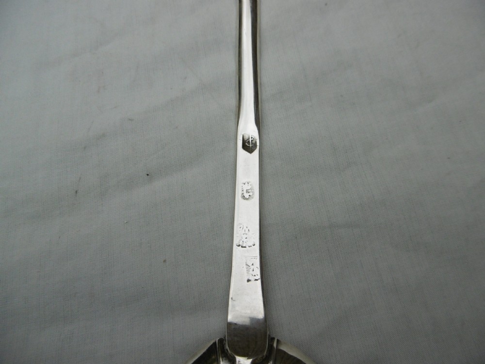 An antique Queen Anne silver marrow spoon showing an oval bowl with a rat-tail joint and a narrow scoop stem stamped with hallmarks. View II